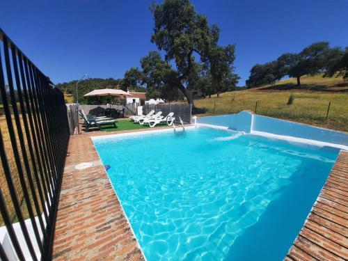 una piscina con agua azul en un patio trasero en CASA RURAL LA DEHESILLA, en Cazalla de la Sierra