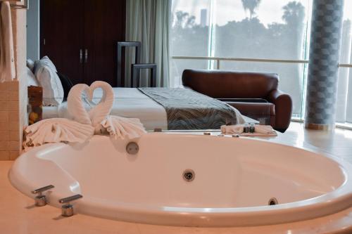 a bath tub in front of a bedroom with a bed at Hotel Portobelo in Guadalajara