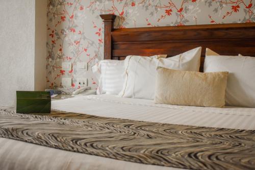 a bed with a wooden headboard and white pillows at Hotel Portobelo in Guadalajara