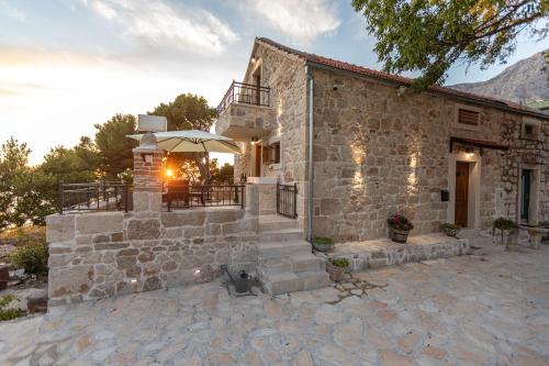 a stone house with a patio and an umbrella at Ivićev san in Tučepi