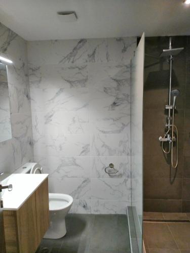 a bathroom with a toilet and a marble wall at Gianni's Apartment By The Sea in Ammouliani