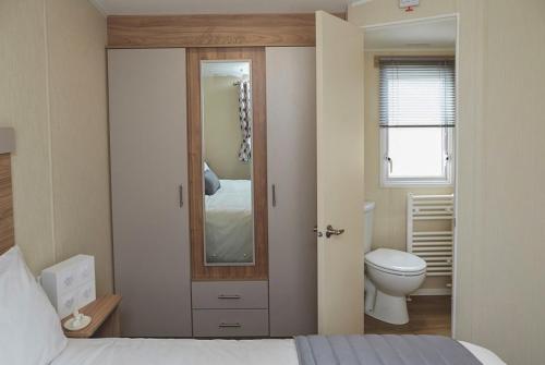 a bedroom with a bed and a toilet and a mirror at Heartsease Cottage in St Austell