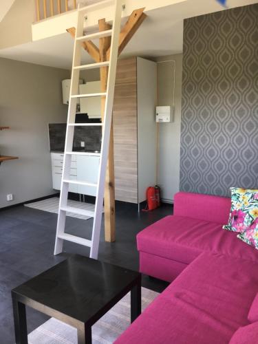 een woonkamer met een roze bank en een ladder bij Stuga nära havet in Ystad