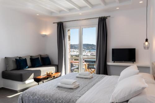 a bedroom with a bed and a couch and a tv at Magic View Suites Mykonos in Mýkonos City
