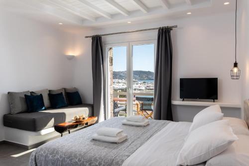 a bedroom with a bed and a couch and a tv at Magic View Suites Mykonos in M&yacute;konos City