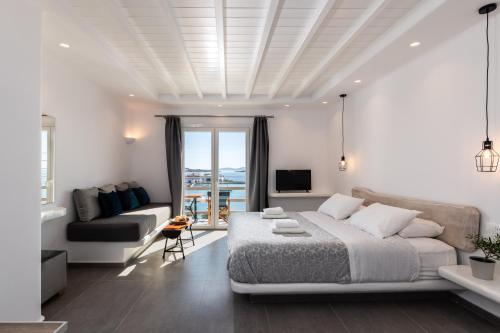 a white bedroom with a bed and a couch at Magic View Suites Mykonos in Mýkonos City