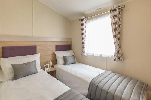 a bedroom with two beds and a window at Heartsease Cottage in St Austell