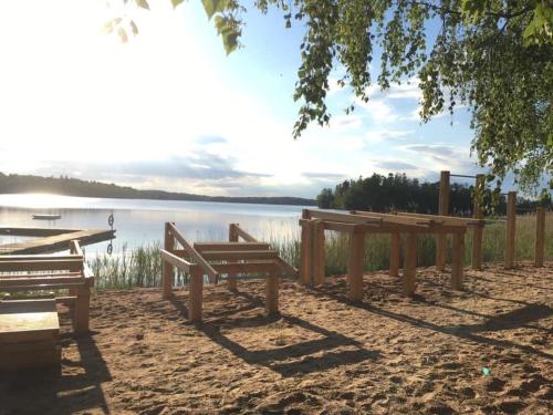 dois bancos sentados na areia perto de um lago em Odensvi Vandrarhem em Odensvi