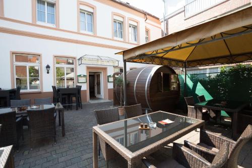 a patio with a table and chairs and a barrel at Hotel Südlohner Hof - Ristorante Da Fabio in Südlohn