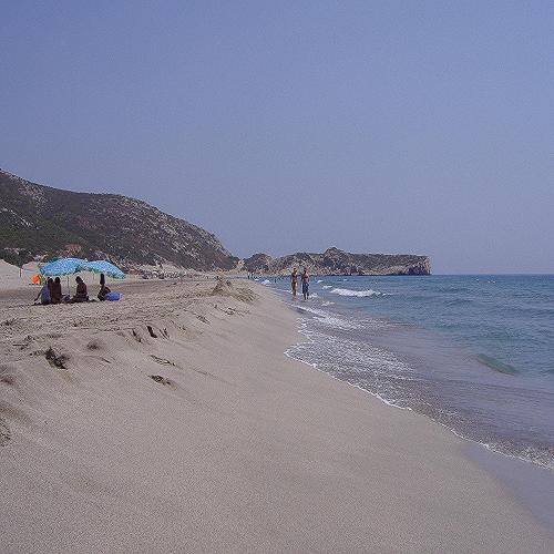 a beach with people sitting under umbrellas and the ocean at Patara Caretta Hotel in Patara