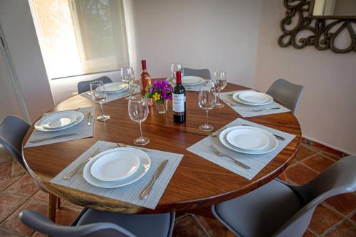 a wooden table with chairs and plates and wine glasses at Casa Marene in Puerto Morelos