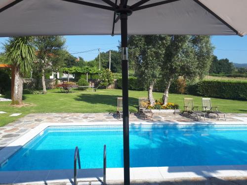 a swimming pool with an umbrella and a yard at Torres de Moreda in A Estrada
