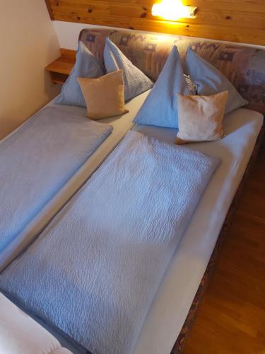a bed with blue sheets and pillows on it at Landhaus Unterköfler in Arriach