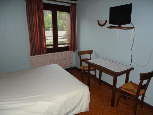 レ・ズッシュにあるChalet La Barme Les Houches Vallée de Chamonixのベッドルーム(ベッド1台、テーブル、テレビ付)