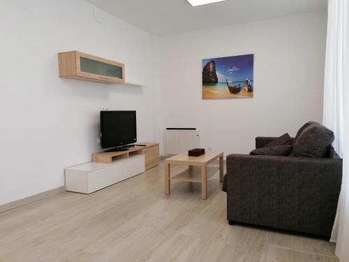 ein Wohnzimmer mit einem Sofa und einem TV in der Unterkunft Apartamento Torre de Hércules in A Coruña