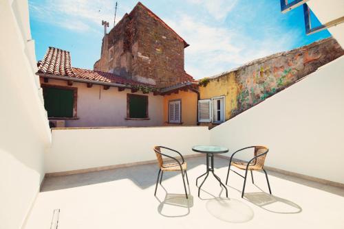 eine Terrasse mit 2 Stühlen und einem Tisch auf einem Gebäude in der Unterkunft Old Town Rooms Piran in Piran