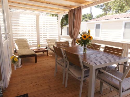 a table and chairs on a porch with a table and flowers at Blue Wave Mobile Home in Biograd na Moru