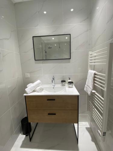 a white bathroom with a sink and a mirror at Le Duplex St Nicolas in Beaune