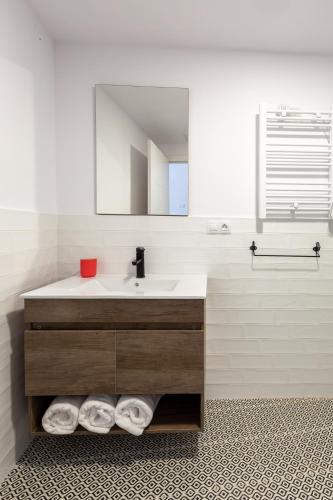 a bathroom with a sink and a mirror and towels at Apartamentos Moreira & Betanzos in Betanzos