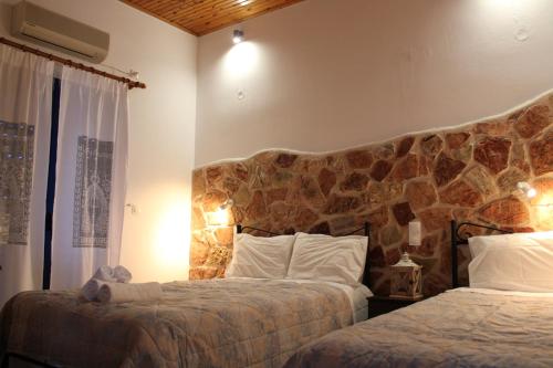 Tentes Holiday Homes في فوناريا: غرفة نوم بسريرين وجدار حجري