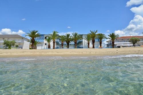 a view of a beach with palm trees and houses at Olympion Beach Hotel in Gerakini