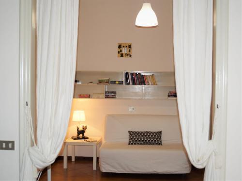 a bedroom with white curtains and a bed and a table at Appartamento Angelina in Stresa