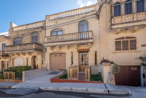Una gran casa de ladrillo con un balcón en la parte superior. en Cloud 9 Residence en Għajnsielem