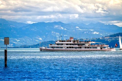 a large boat on the water with mountains in the background at Auszeit Apartment LAKESIDE mit Privatstrand in Friedrichshafen