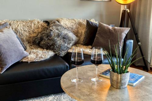 a couch with two glasses of wine on a table at Auszeit Apartment LAKESIDE mit Privatstrand in Friedrichshafen