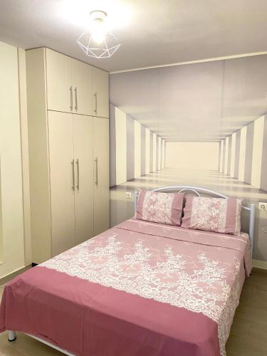 a bedroom with a pink bed and white cabinets at La Petite Maison Nicole in Thessaloniki