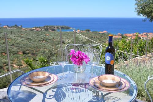 a glass table with a bottle of wine and a bowl of flowers at Athina's Stone House in Kardamyli in Kardamili