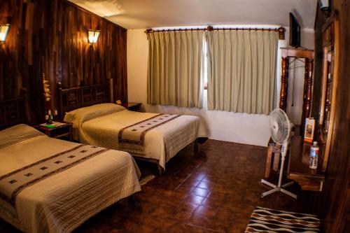 Habitación de hotel con 2 camas y ventilador en Meson Yohualichan, en Cuetzalán del Progreso