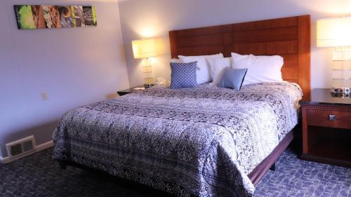 a hotel room with a large bed and two lamps at Copper Lantern Motor Lodge in West Brookfield