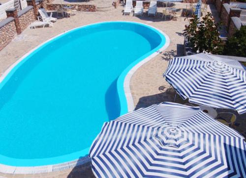 twee parasols naast een zwembad bij Babis Hotel in Karterados