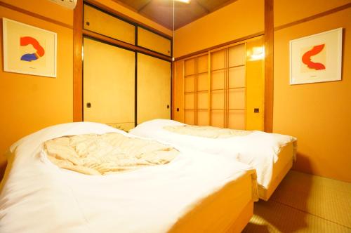 two beds in a room with yellow walls at Momiji Takayama in Takayama