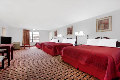 um quarto de hotel com três camas com lençóis vermelhos em Lone Star Inn Vernon em Vernon