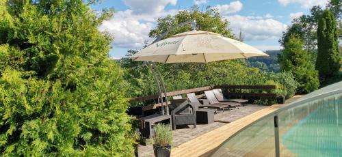an umbrella and chairs next to a swimming pool at hotel ZLATÝ POTOK in Nicov