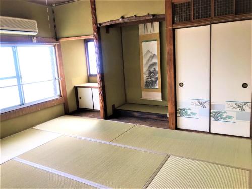 um quarto vazio com duas portas e uma janela em ゲストハウス三軒家 em Shirahama