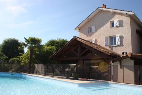 uma casa e uma piscina em frente a uma casa em LA DOLOREANNE em Saint-Didier-sur-Chalaronne