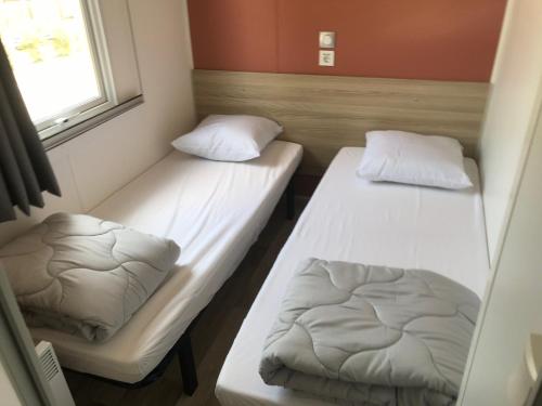 2 Betten in einem kleinen Zimmer mit Fenster in der Unterkunft MOBIL HOME camping le Mar Estang bord de plage in Canet-en-Roussillon