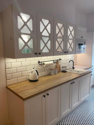 a kitchen with white cabinets and a wooden counter top at Apartament BellaPola Loft in Nysa