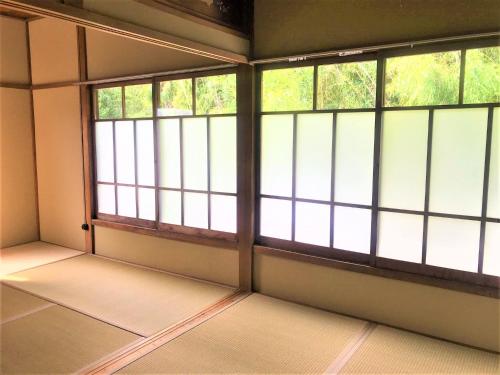 an empty room with windows in a building at ゲストハウス三軒家 in Shirahama