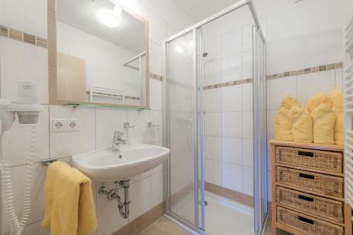 a white bathroom with a sink and a shower at Alpenjuwel Appartements in Flachau