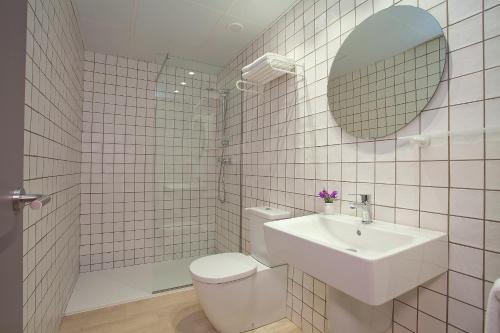 a bathroom with a toilet and a sink and a mirror at Apartamentos Ribera in Benidorm