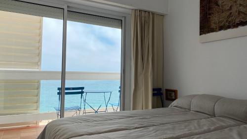 a bedroom with a large window with a view of the ocean at Mediterranean apartment in Lloret de Mar next to the Sea in Lloret de Mar