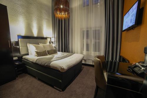 um quarto de hotel com uma cama e uma televisão em Hotel Mansion em Amsterdã