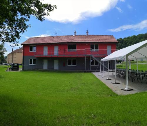 a red building with tables and a tent in a field at Penzion Sloup in Sloup