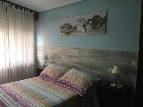 ヒホンにあるApartamento Calle Corrida de Gijonのベッドルーム1室(ストライプ掛け布団付きのベッド1台付)