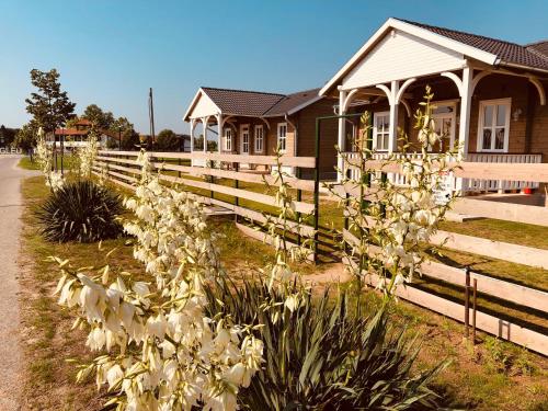 a fence in front of a house with white flowers at Club Thermal Village Cegled in Cegléd