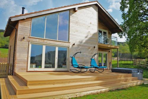 a house with a deck with two chairs on it at Blackdown Views - New 6 Bedroom Eco House in Dunkeswell